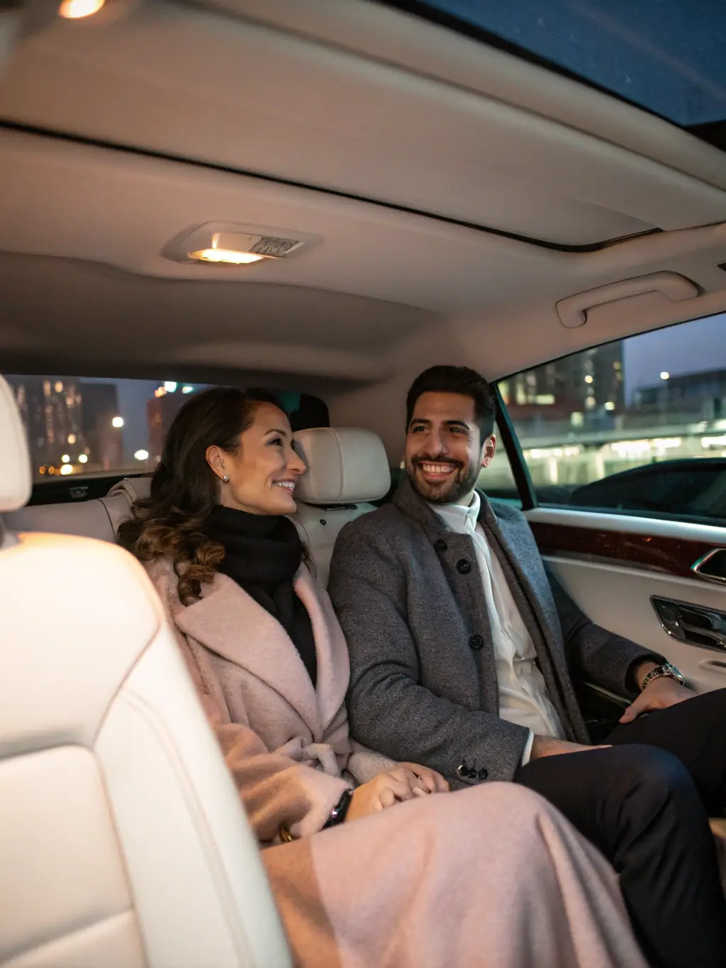 A relaxed passenger in the back of an FW Limo sedan, using a tablet, with the Montreal skyline visible through the window, conveying a stress-free experience.